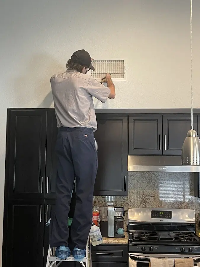 Technician inspecting an air vent during HVAC service in Westminster
